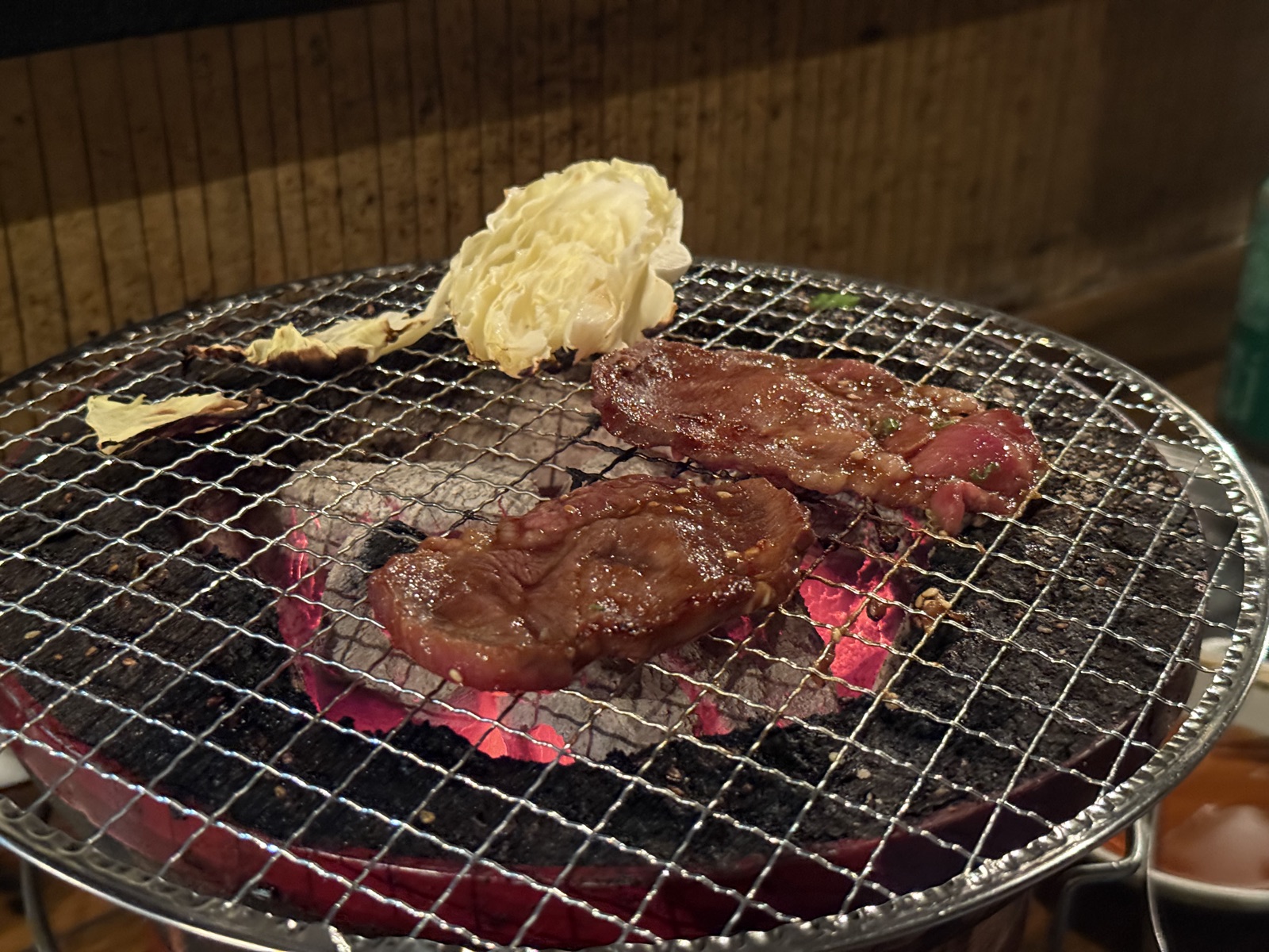 Charcoal-grilled beef cuts on mesh with daikon, Japanese yakiniku.